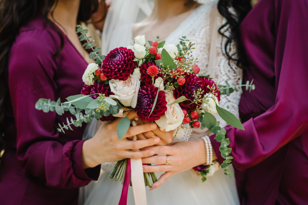 A bride and bridesmaids in autumnal tones of deep red - how to plan an autumn wedding